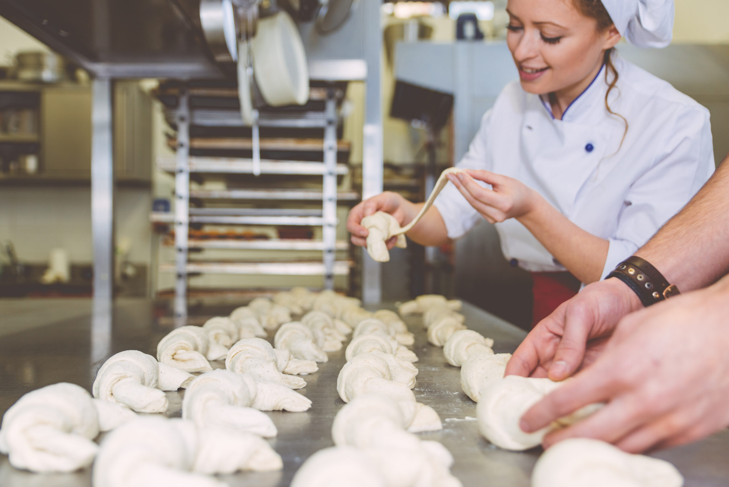 Chef preparing sweet croissant in the pastry shop laboratory. Industrial concept about food
